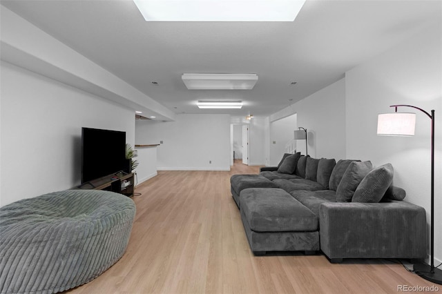 living room featuring baseboards, a skylight, and light wood-style floors