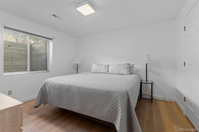 bedroom featuring baseboards, visible vents, and wood finished floors