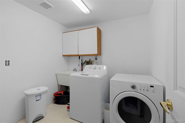 clothes washing area featuring cabinet space, visible vents, and washer and clothes dryer