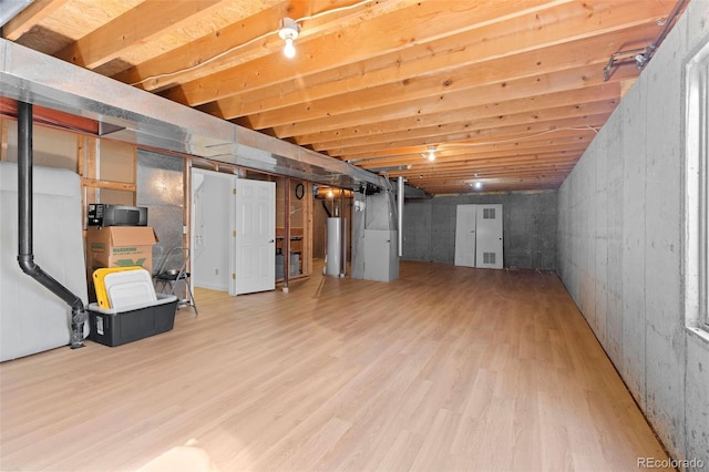 unfinished below grade area with water heater, visible vents, and wood finished floors