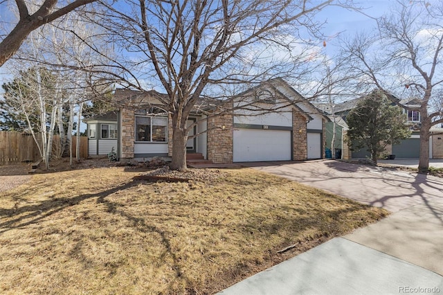 single story home featuring a garage, driveway, stone siding, and fence