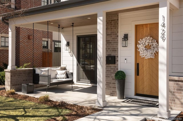 property entrance with covered porch and brick siding