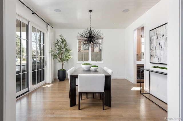 dining space featuring baseboards, a chandelier, and light wood-type flooring