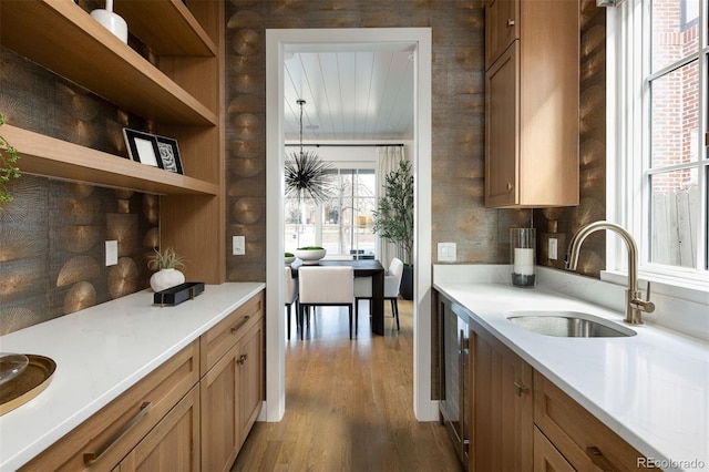 kitchen featuring wood finished floors, a sink, open shelves, and brown cabinets