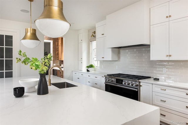 kitchen featuring a sink, decorative backsplash, white cabinetry, and stainless steel gas stove