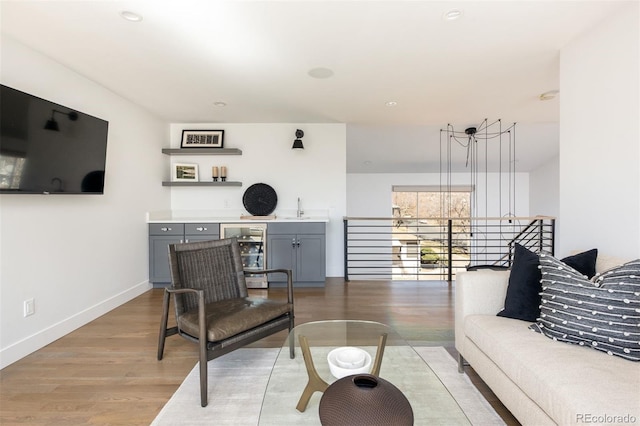 living area featuring light wood-style flooring, recessed lighting, baseboards, and beverage cooler