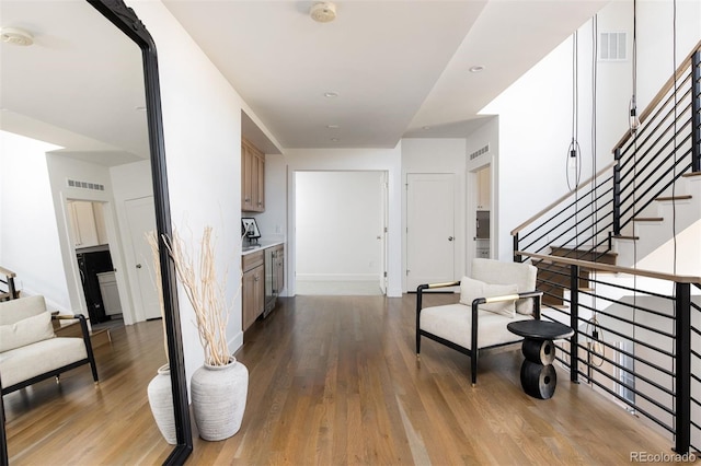 corridor featuring wood finished floors, stairway, and visible vents