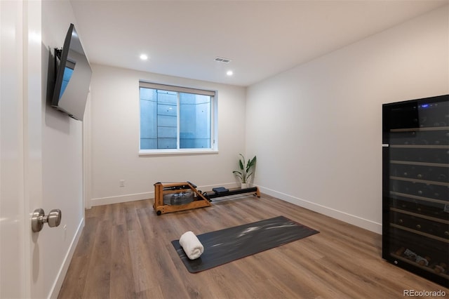 exercise area featuring wood finished floors, baseboards, wine cooler, and visible vents