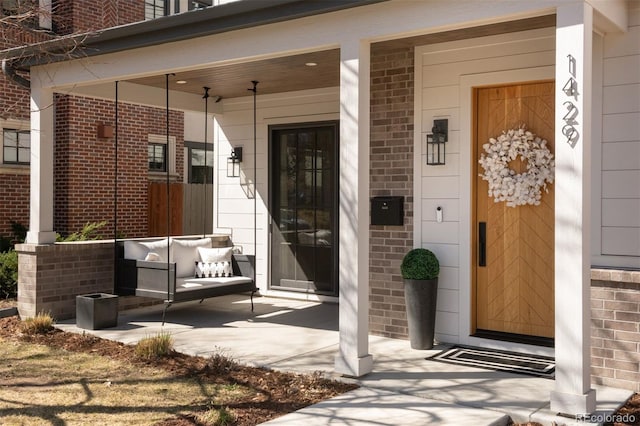 view of exterior entry with covered porch and brick siding