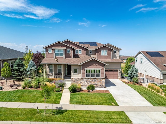 craftsman-style house with a porch, a garage, a front yard, and solar panels