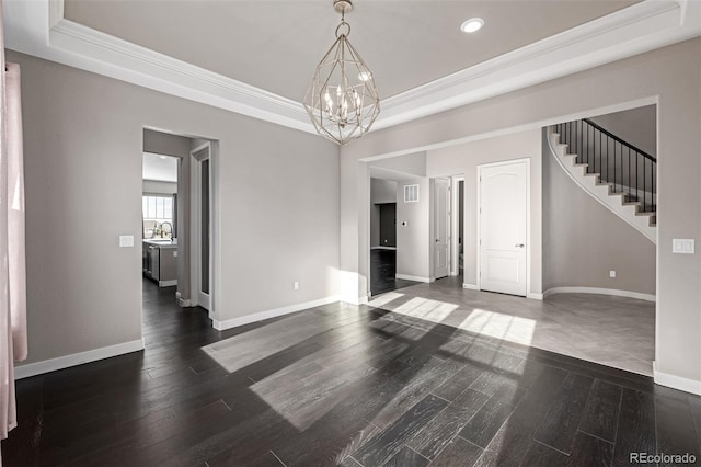 spare room with a raised ceiling, dark wood-type flooring, sink, and a chandelier