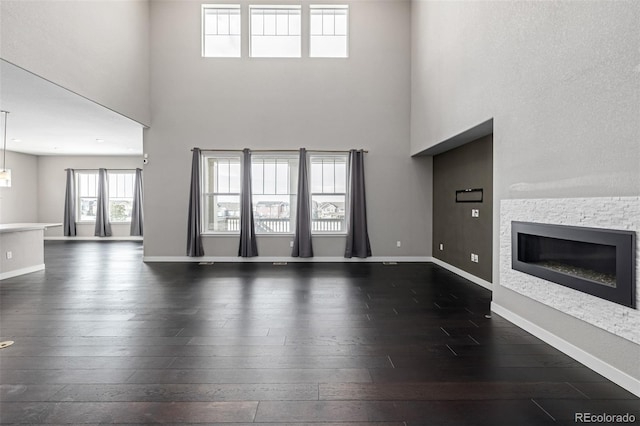 unfurnished living room with a high ceiling and dark hardwood / wood-style floors