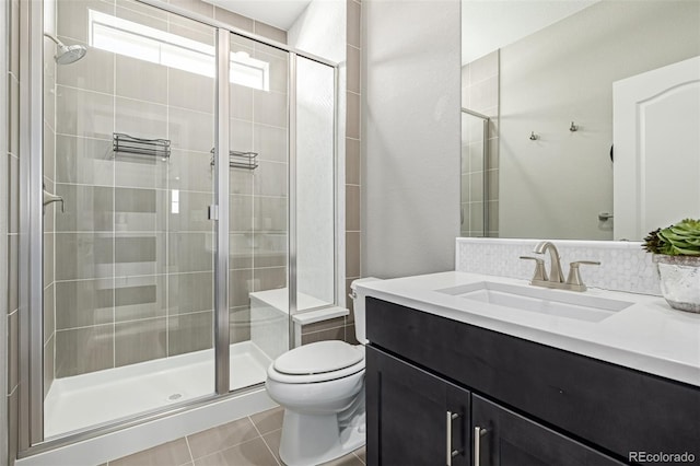 bathroom with backsplash, tile patterned flooring, vanity, toilet, and a shower with door