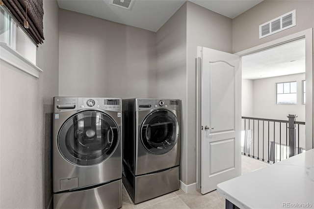 clothes washing area featuring light tile patterned floors and washing machine and dryer