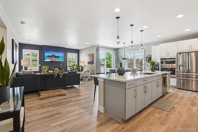 5680 Saddle Skirt St, Parker, CO 80134 - kitchen featuring stainless steel appliances, open floor plan, light countertops, an island with sink, and recessed lighting