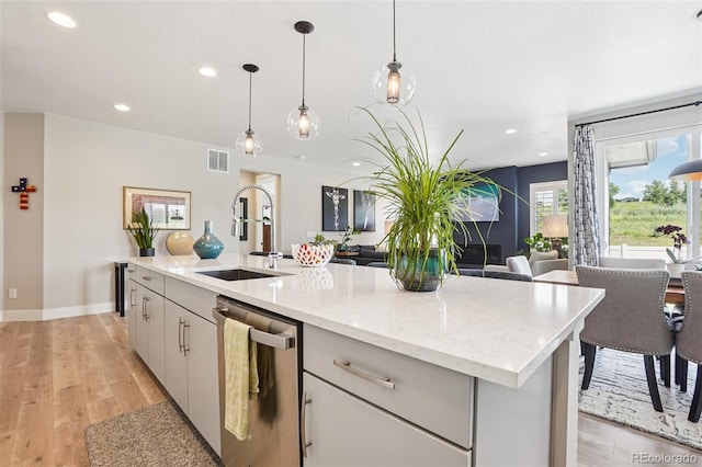 5680 Saddle Skirt St, Parker, CO 80134 - kitchen with stainless steel dishwasher, open floor plan, light wood-style flooring, hanging light fixtures, and recessed lighting
