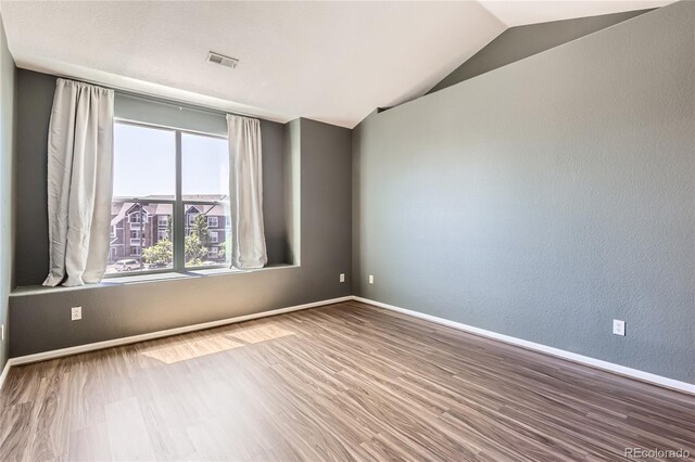 14251 E 1st Dr Unit 305, Aurora, CO 80011 - spare room with wood finished floors, vaulted ceiling, and a textured wall