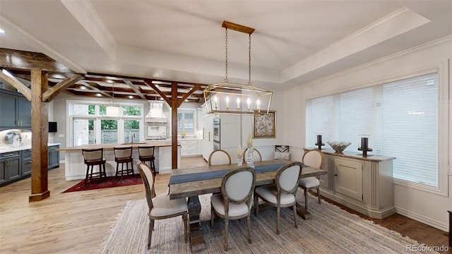 dining space featuring a tray ceiling, light wood-style flooring, and crown molding