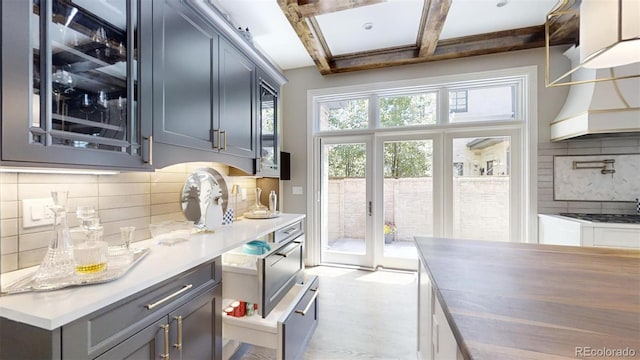 kitchen featuring pendant lighting, backsplash, gas stovetop, and beamed ceiling