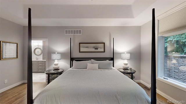 bedroom with a raised ceiling and wood-type flooring