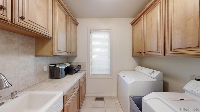 washroom featuring cabinets, light tile patterned floors, sink, and washing machine and clothes dryer