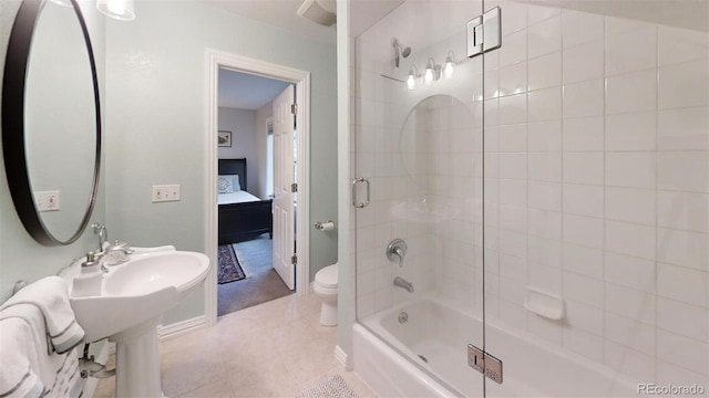 bathroom with tile patterned floors, shower / bath combination with glass door, and toilet