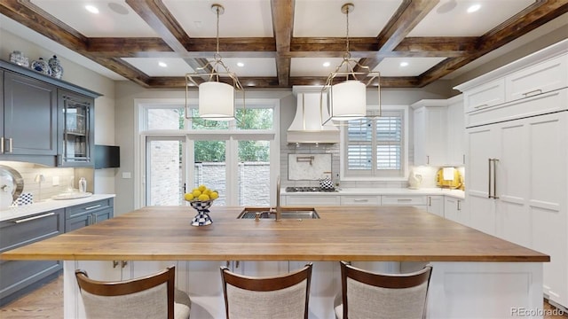 kitchen featuring butcher block countertops, backsplash, and an island with sink