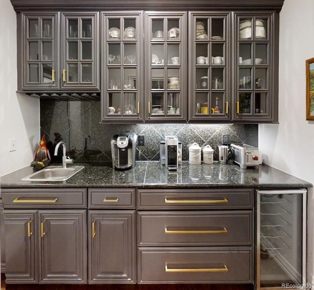 bar featuring tasteful backsplash, sink, beverage cooler, and dark brown cabinetry