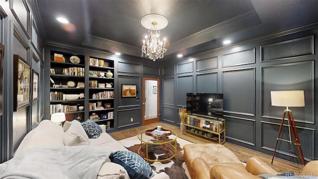 living room featuring a raised ceiling, light wood-type flooring, an inviting chandelier, and built in shelves