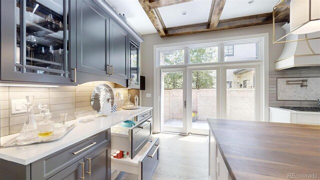 kitchen with beam ceiling, tasteful backsplash, light countertops, gas cooktop, and coffered ceiling