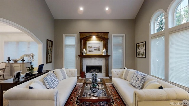 living room with arched walkways, lofted ceiling, recessed lighting, and a premium fireplace