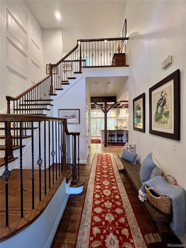 stairs with a high ceiling, baseboards, and wood finished floors