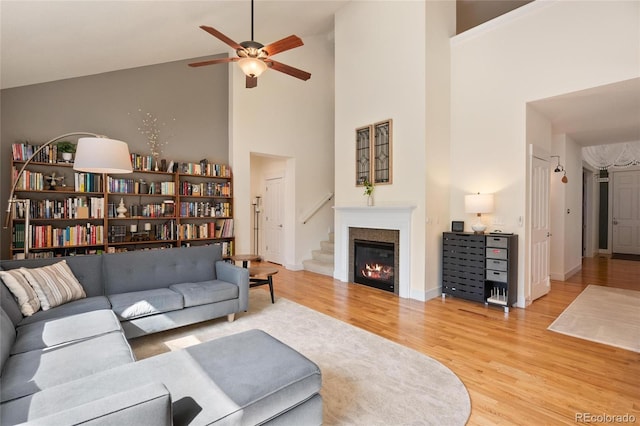 living room with ceiling fan, wood-type flooring, and a towering ceiling