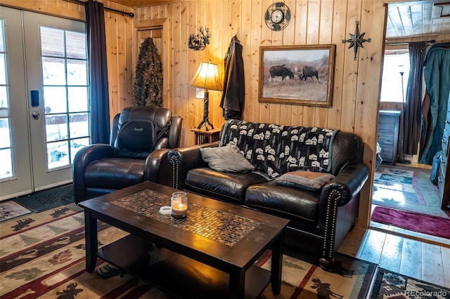 living room with wood walls, wood-type flooring, and french doors