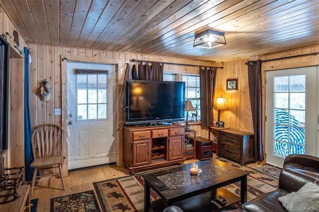 living area with light wood-type flooring, wooden ceiling, and wooden walls