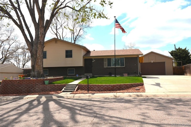 tri-level home featuring an outdoor structure, brick siding, a front yard, and a detached garage