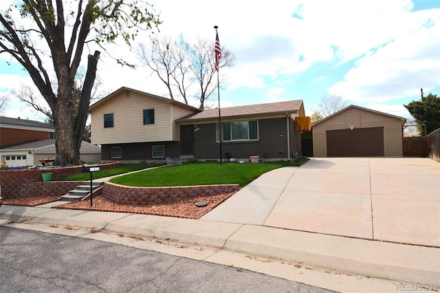 split level home featuring fence, a front lawn, brick siding, a detached garage, and an outbuilding