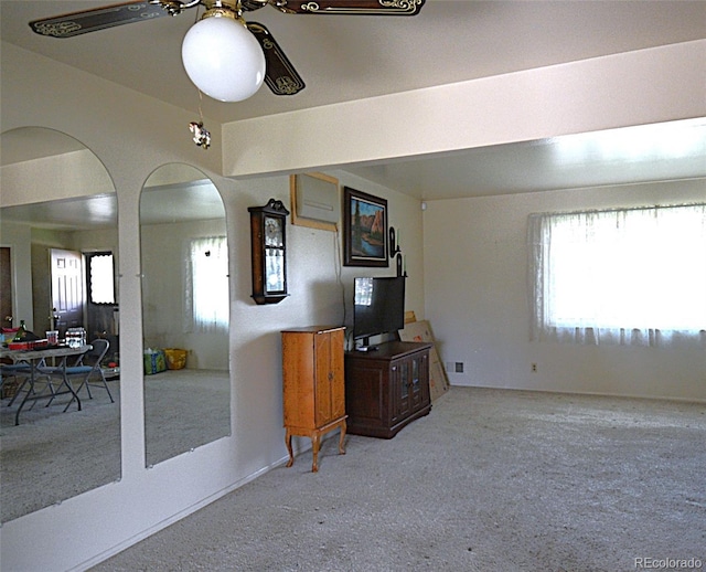 interior space with arched walkways, a ceiling fan, and carpet flooring