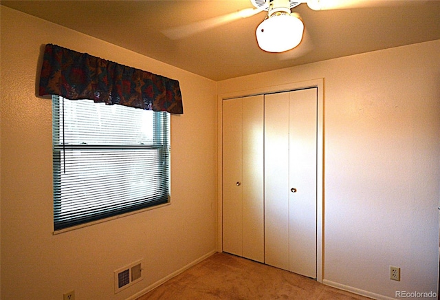 unfurnished bedroom featuring visible vents, a closet, light carpet, baseboards, and ceiling fan