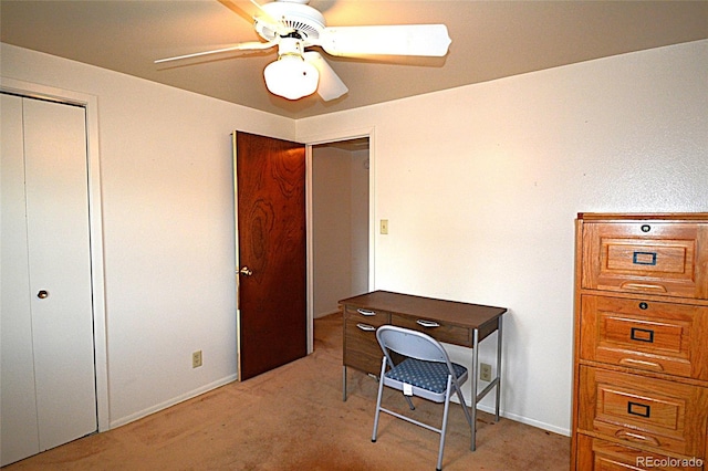office area with a ceiling fan, baseboards, and light carpet