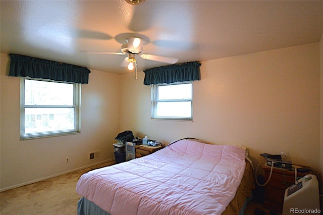 bedroom with light colored carpet, a ceiling fan, and baseboards