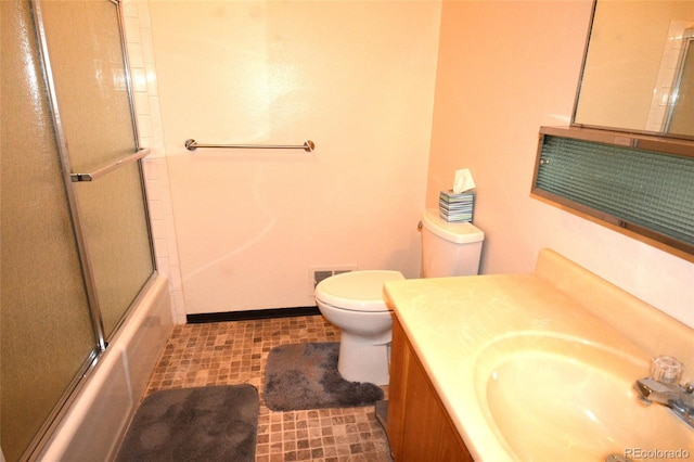 full bath featuring vanity, visible vents, toilet, baseboards, and combined bath / shower with glass door