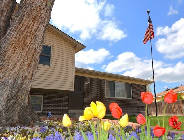 view of side of home with brick siding and fence