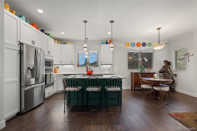 kitchen with stainless steel appliances, a kitchen island, pendant lighting, a breakfast bar, and white cabinets