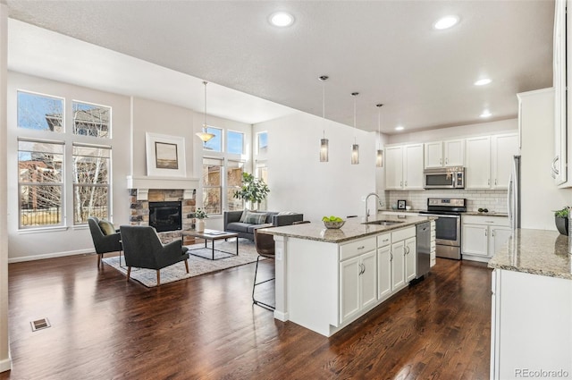 kitchen with visible vents, a sink, open floor plan, stainless steel appliances, and dark wood-style flooring