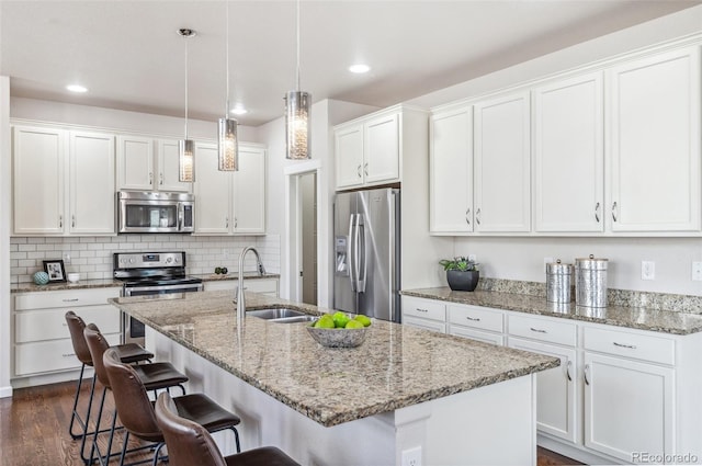 kitchen featuring a breakfast bar area, dark wood-style floors, white cabinets, stainless steel appliances, and a sink