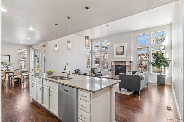 kitchen featuring dark wood-type flooring, a sink, stainless steel dishwasher, white cabinets, and a fireplace