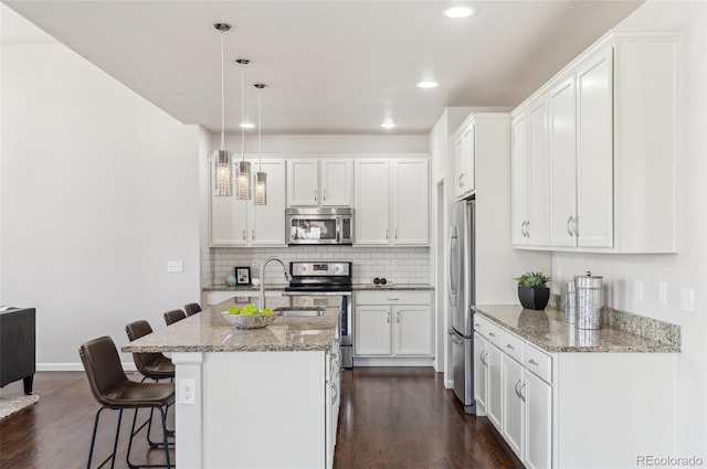 kitchen featuring dark wood-type flooring, decorative backsplash, appliances with stainless steel finishes, white cabinetry, and a sink