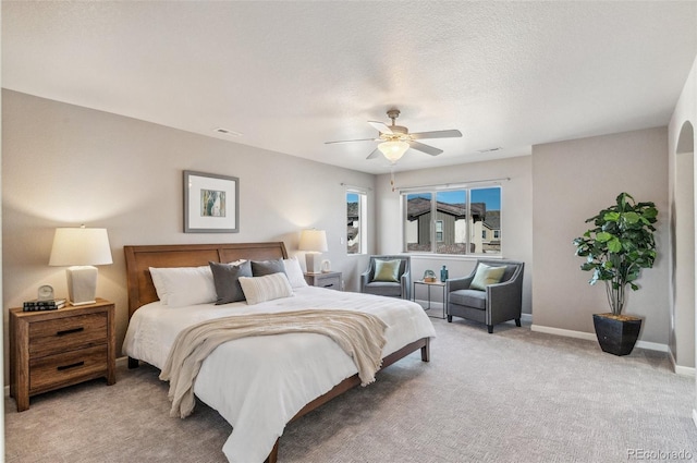 bedroom featuring visible vents, baseboards, ceiling fan, a textured ceiling, and light colored carpet