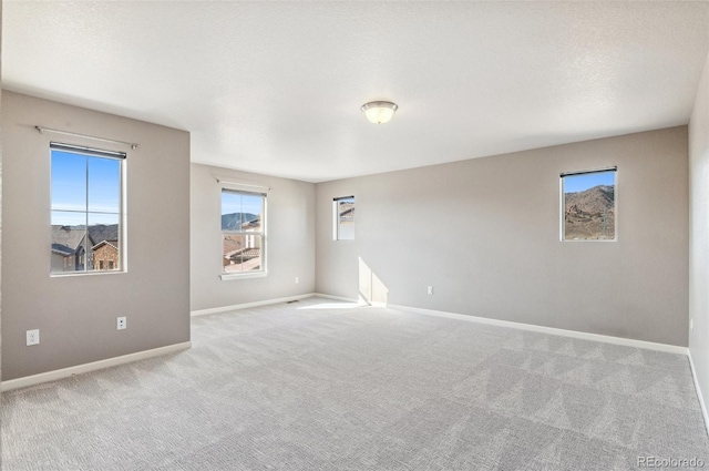 unfurnished room featuring baseboards, carpet floors, and a textured ceiling